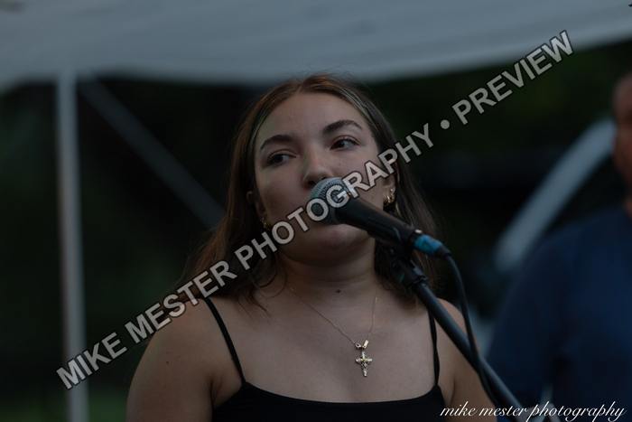 Female vocalist singing beneath the outdoor stage canopy.