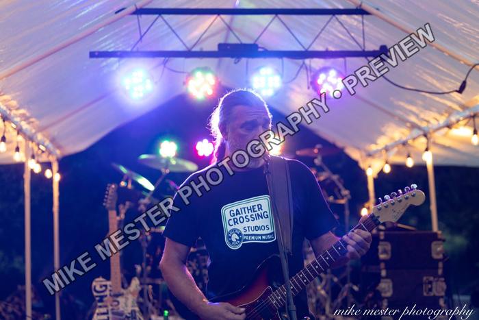 Guitarist playing beneath blue, pink, and amber stage lights.