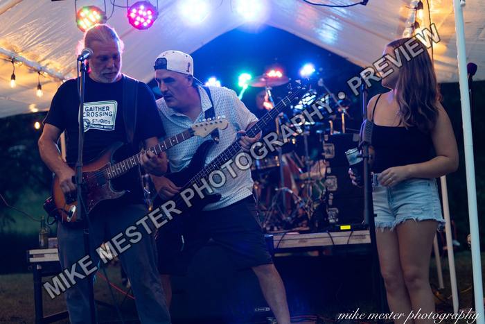 Vocalist singing beside two guitarists during the live performance.